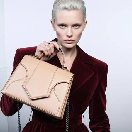 Handbag The Vesta This bag is a symphony of feminine power and masculine structure. Its body is inspired by the delicate curve of a woman’s waist, while its overall silhouette evokes the look of powerful, daring shoulders. This tension culminates in the flap, whic